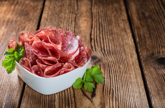 Old wooden table with sliced Salami