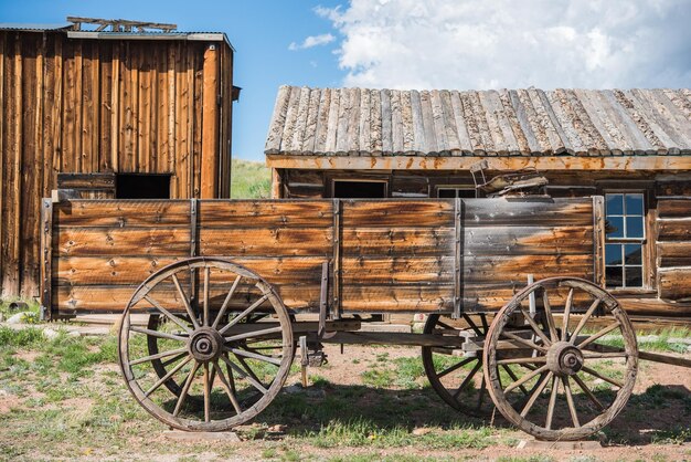 Old Wooden Wagon and Aged Log Cabins