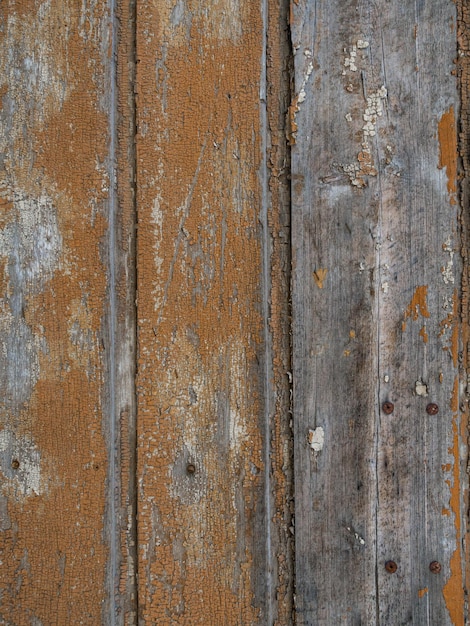 An old wooden wall texture with peeling faded brown paint