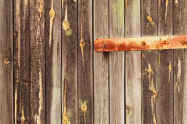 An old wooden weathered door with a metal hinge