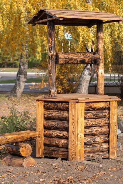 Vecchio pozzo di legno fatto di tronchi in giardino, design del terreno da giardino