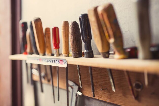 Vecchi strumenti per la lavorazione del legno sul muro, retro colorato