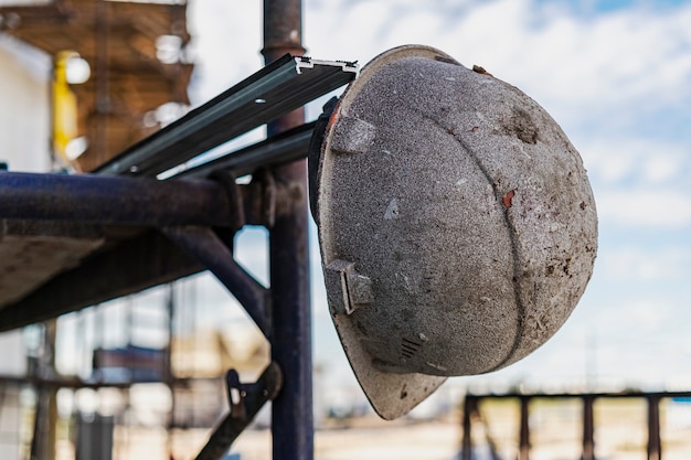 An old work helmet hangs on the scaffolding. Blurred background. Builder hard work concept.