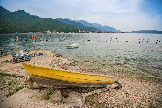 Old yellow boat on the shore near the mussel and oyster farm along the coast of the Bay of Kotor