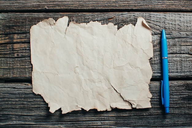 Old yellow paper on wooden table Radom is a pen