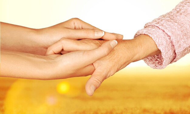 Old and young hands together on blurred background