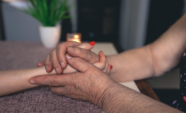 Photo old and young man holding hands close up