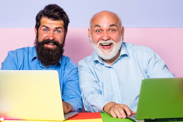 Old and young men working on laptops