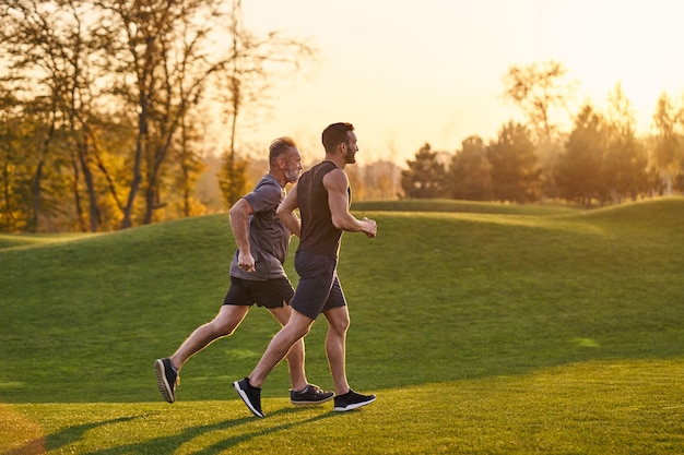 The old and young sportsmen running in the green park