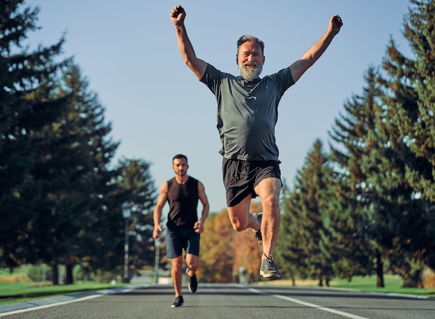 The old and young sportsmen running on the road