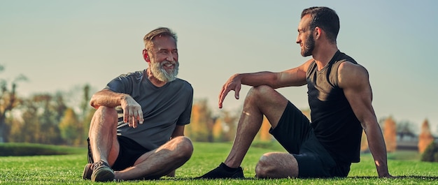 The old and young sportsmen sitting on the grass