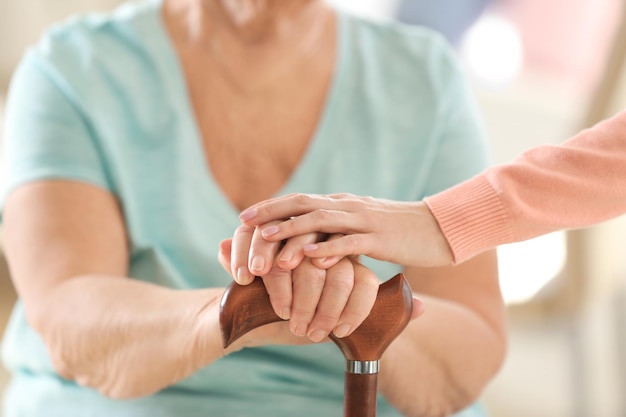 Old and young women holding hands on walking stick closeup