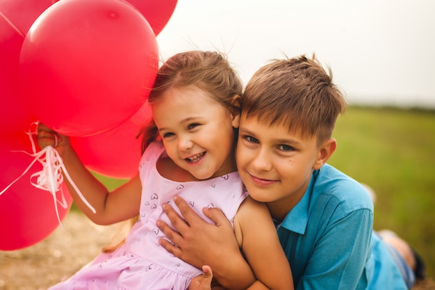 older brother hugs sister in the summer in nature