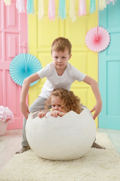 Older brother take care about his little sister is sitting in a white egg that hatched