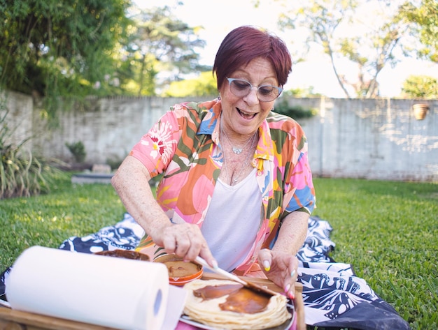 older lady preparing pancakes in the park with sweet milk