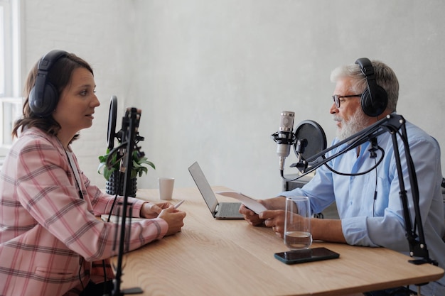 Older man and female presenter in a recording studio create a podcast senior woman radio presenter or interviewer