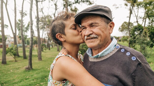 older man getting a kiss from his very yellow daughter in the park