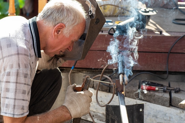 older man in a protective mask welding