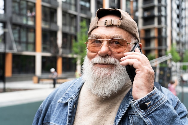 Фото Пожилой мужчина разговаривает по смартфону на открытом воздухе в городе