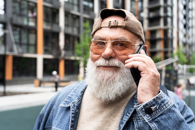 Foto uomo più anziano che parla su smartphone all'aperto in città