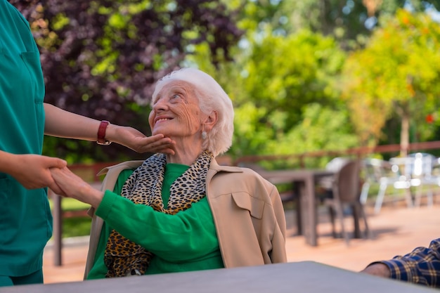 An older or mature woman with the nurse in the garden of a nursing home in a moment of affection