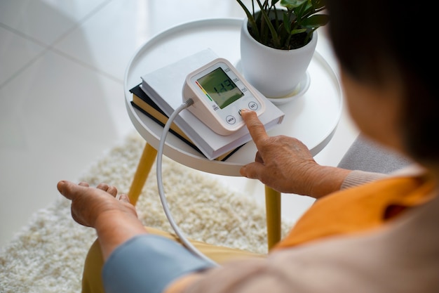 Foto persona anziana che controlla la pressione sanguigna con il tensiometro