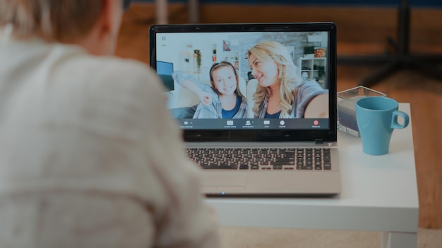 Older person talking to family on videoconference call, meeting\
to chat with daughter and little girl. senior woman using laptop\
computer with online remote teleconference for conversation.