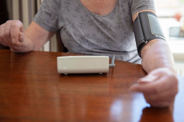 An older senior woman checks her blood pressure at home health care concept