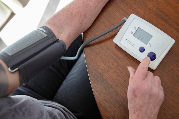 An older senior woman checks her blood pressure at home health care concept