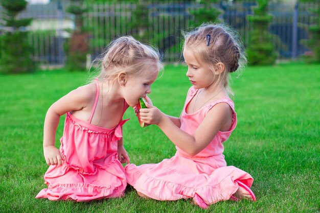 Older sister feeding younger piece of watermelon on a hot summer day