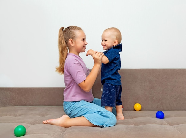 The older sister holds the hands of her younger brother