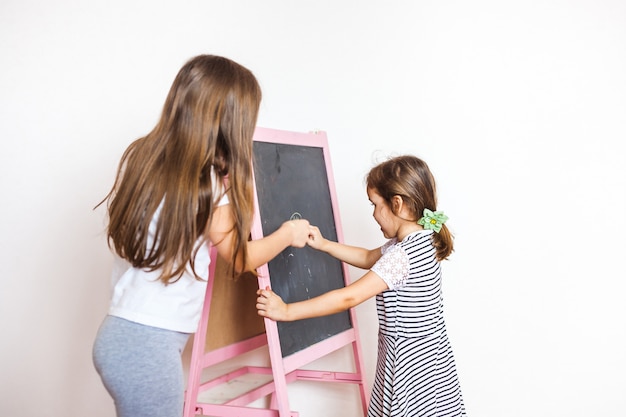 Older sister teaches younger on chalk board