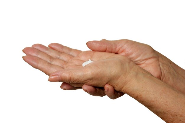 Older woman applying cream on hands closeup