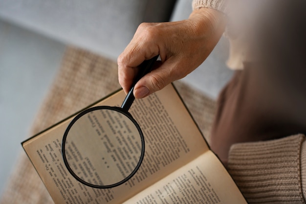 Photo older woman reading while using a magnifying glass