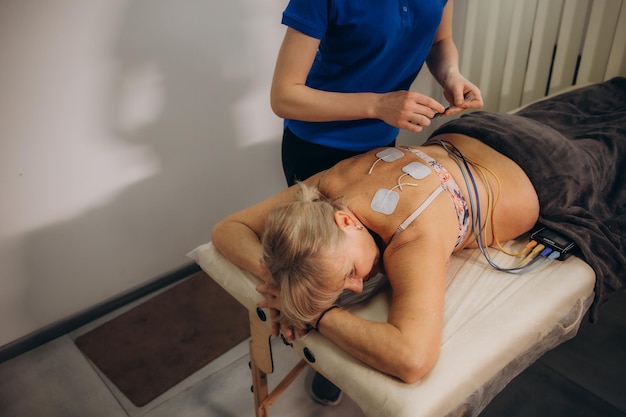 An older woman in a rehabilitation center undergoing an electromyostimulation procedure