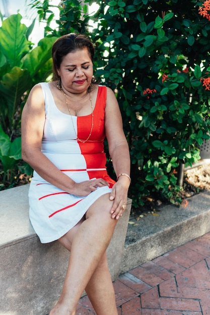 Older woman sitting in park with knee pain. Concept of arthritis pain.