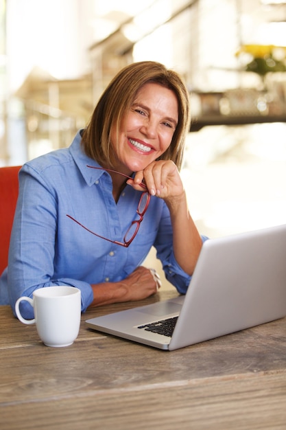 Older woman sitting at table working with laptop