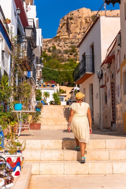 An older woman tourist visiting the Santa Cruz neighborhood in Alicante Mediterranean house Travel for the elderly