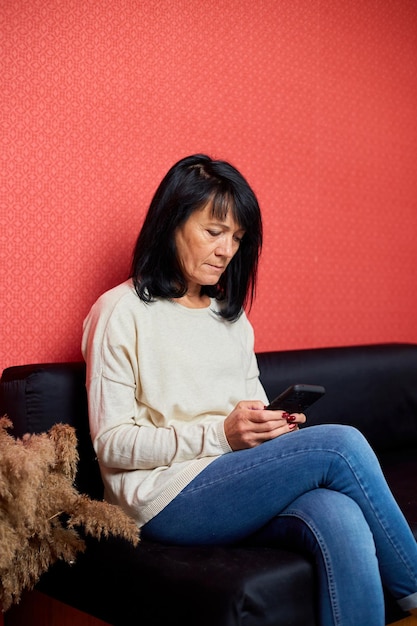年配の女性は、スマートフォンを使用してメッセージ チャットを入力します