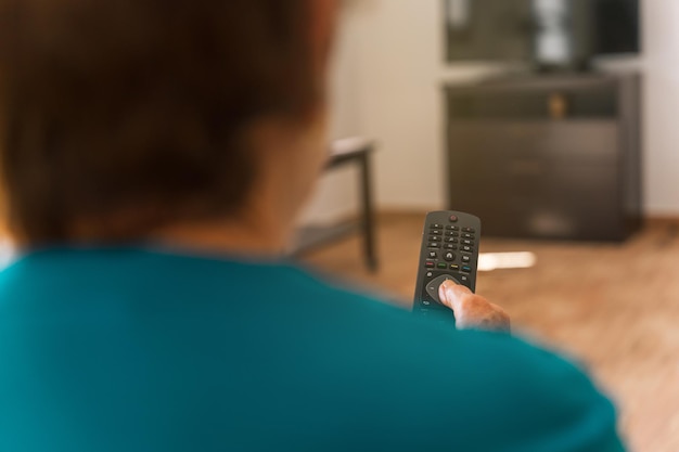 Foto donna anziana irriconoscibile tramite il telecomando della tv