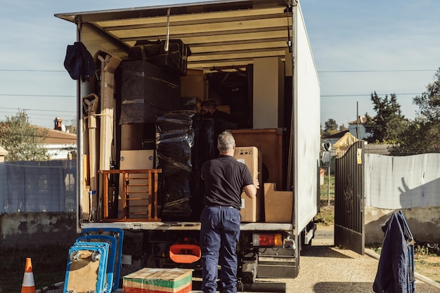 Foto lavoratore più anziano che carica scatole di cartone su un camion in movimento