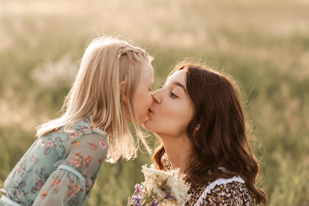 Older and younger sisters walk together in nature in the summer. sister hugs and soothes