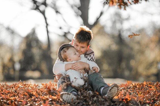 Foto il bambino più grande abbraccia e comunica con il suo fratello di 6 mesi i bambini seduti nel parco trascorrono del tempo insieme