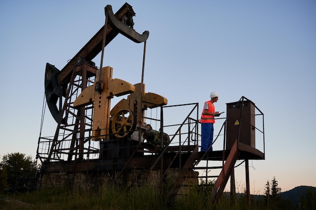 Olieman die het werk van de krik van de petroleumpomp controleert