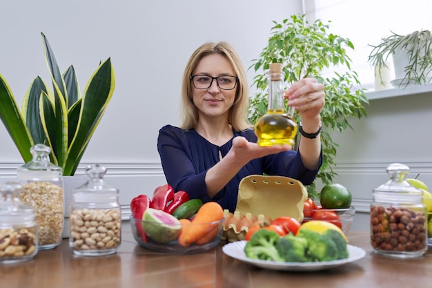 Olijfolie in fles in de hand van vrouw voedingsdeskundige gezonde voeding gezonde levensstijl