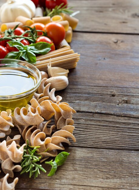 Olijfolie, pasta, knoflook en tomaten op bruin houten tafel close-up met kopie ruimte