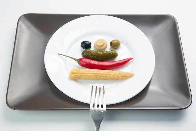 Olijven, ingelegde komkommer, paprika, champignons en maïs in een salade op een bord. voedsel en groenten. dieet en gewichtsverlies