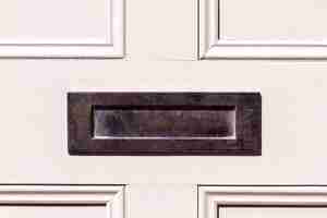 Photo olished steel letterbox on a white wooden front door