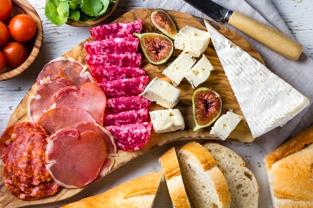 Photo olive board with salami, ham serrano, cheese, nuts and ciabatta bread