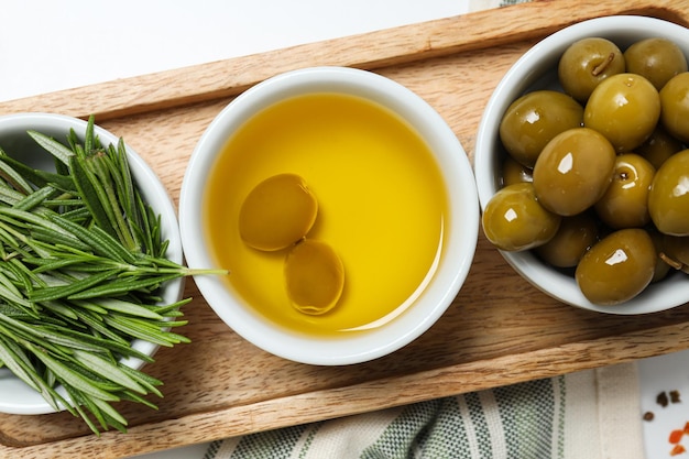 Olive branches oil and olives in bowls towel on white background close up
